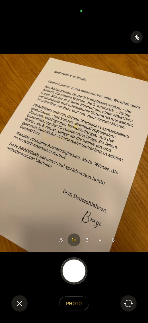 Phone camera photographing a printed German letter lying on a wooden table